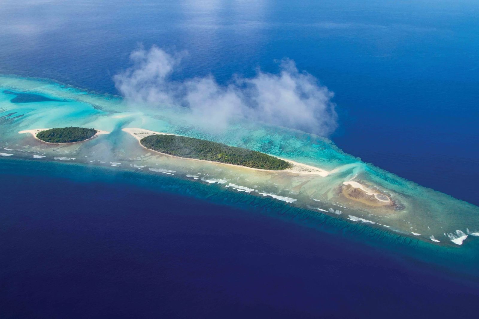 Aerial view of a remote Pacific atoll — reef, islets, open ocean